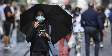 passantin mit regenschirm und maske in corona-krise
