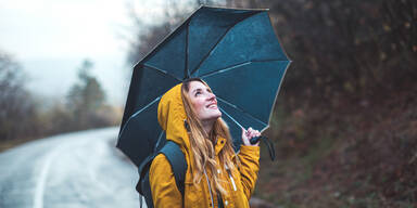 Frau mit Regenschirm schaut zum Himmel