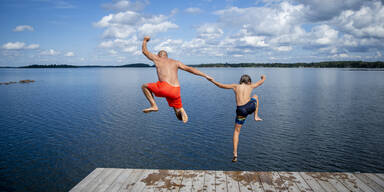 Badewetter: Mann und Kind springen in See