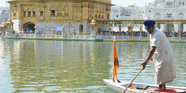Ein Mann säubert das Wasser beim Goldenen Tempel in Amritsar (Indien)